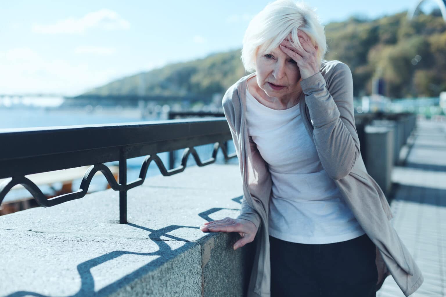 Older woman having a dizzy spell while out for a walk.