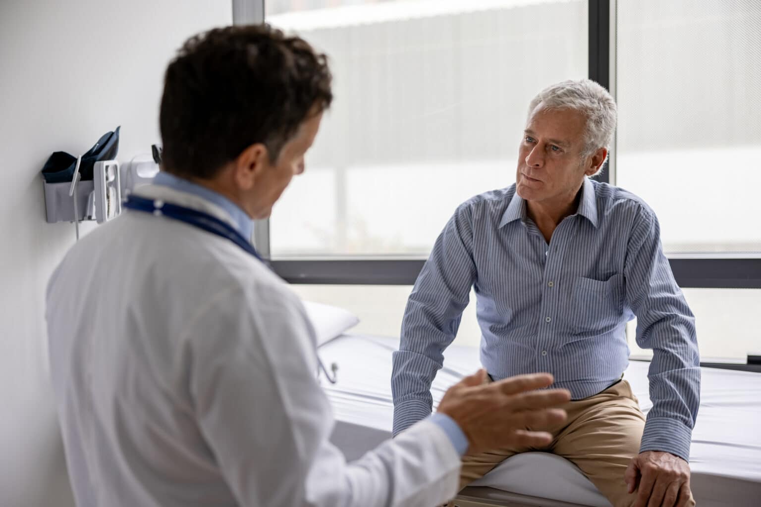 Doctor talking to a patient in a consultaton at his office practice - health care and medicine concepts