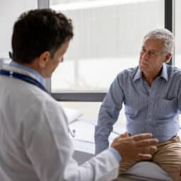 Doctor talking to a patient in a consultaton at his office practice - health care and medicine concepts