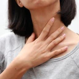 Woman with sore throat touching her neck.