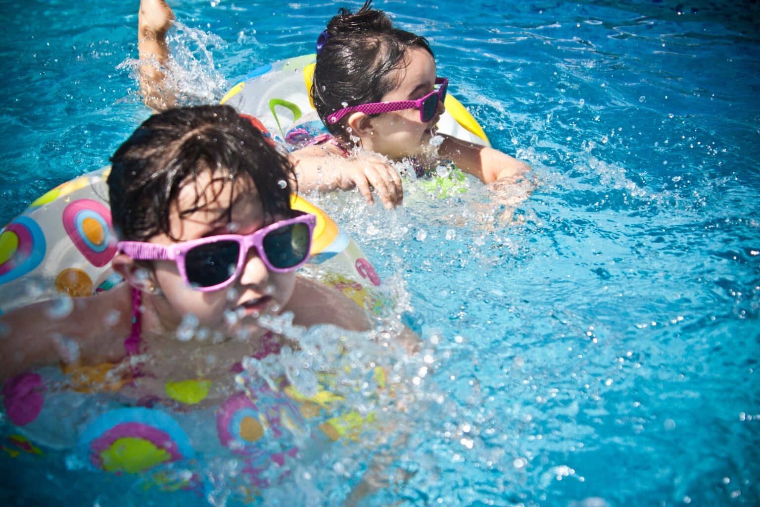 Two young girls swimming in a pool.