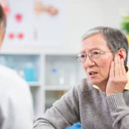 Senior man telling a doctor about his ear pain
