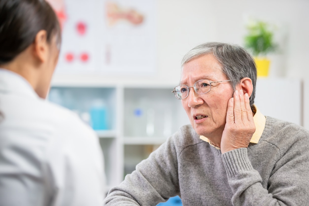 Senior man telling a doctor about his ear pain.