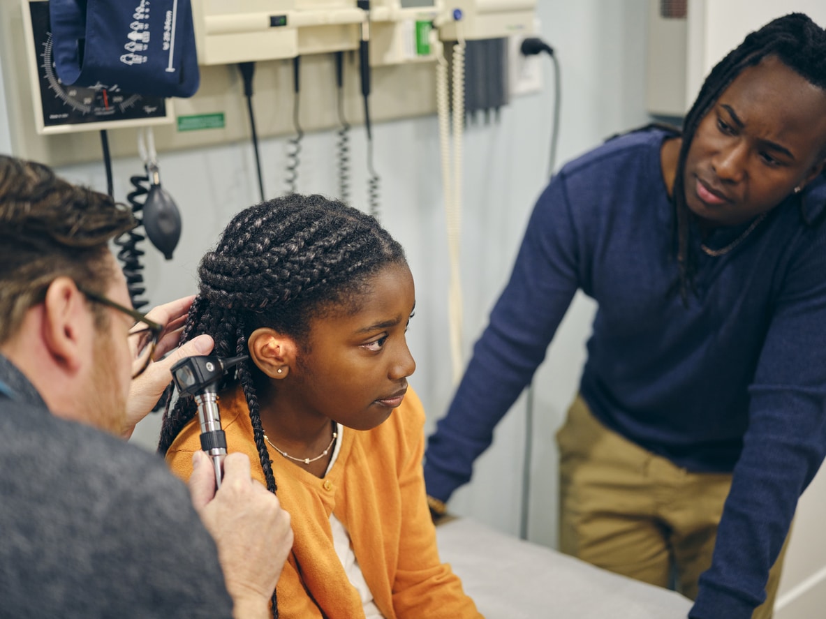 Young girl gets ear examined by doctor