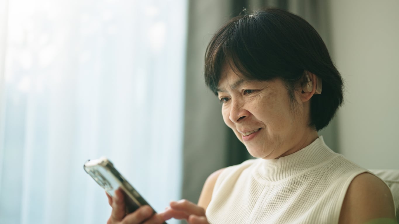 Woman with a hearing aid using a phone.