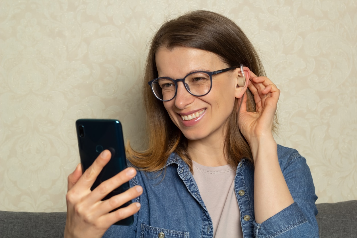 Woman with hearing aid talks on phone