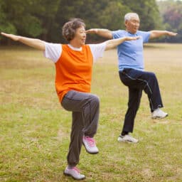 senior couple balancing on one foot each in the park